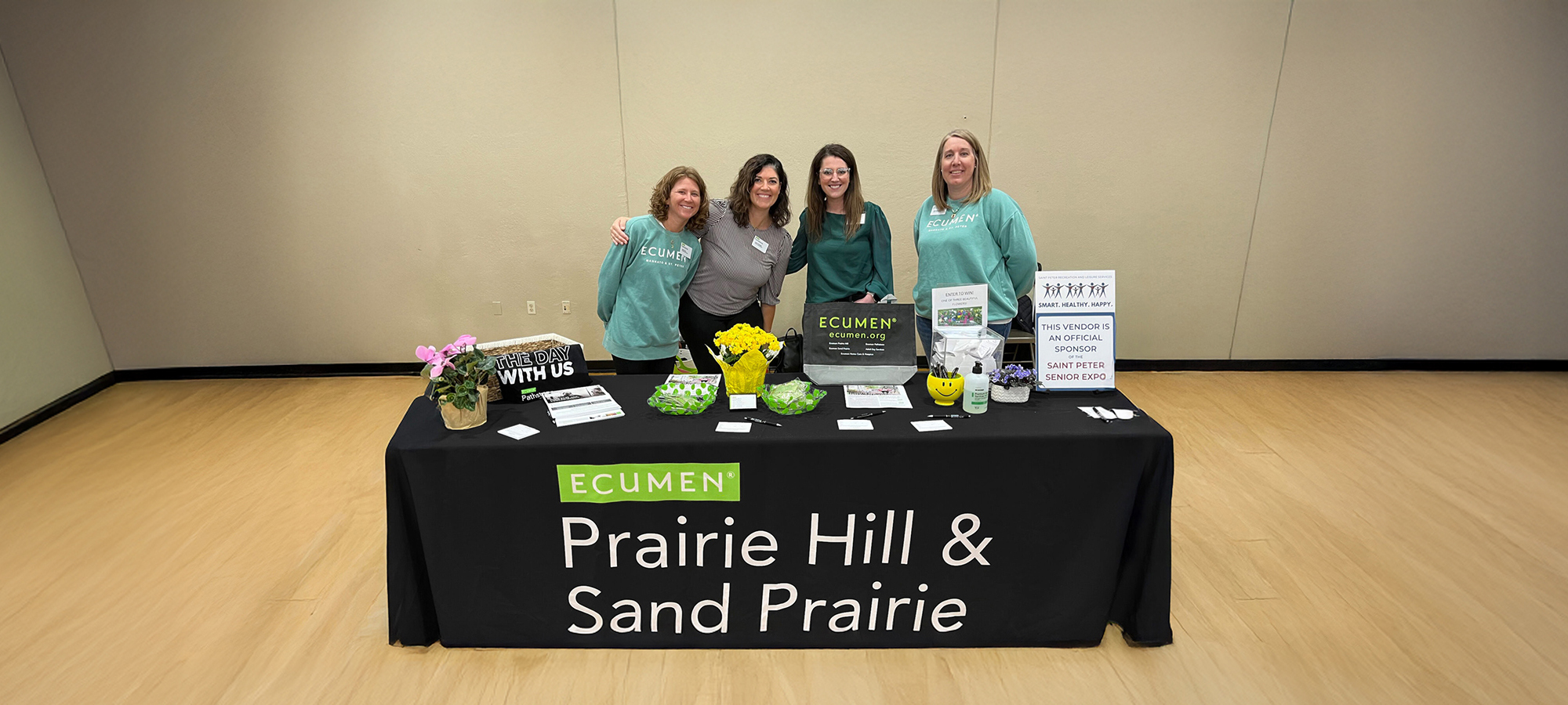 Team members of Ecumen Prairie Hill and Sand Prairie smiling while working at an exhibitors' booth
