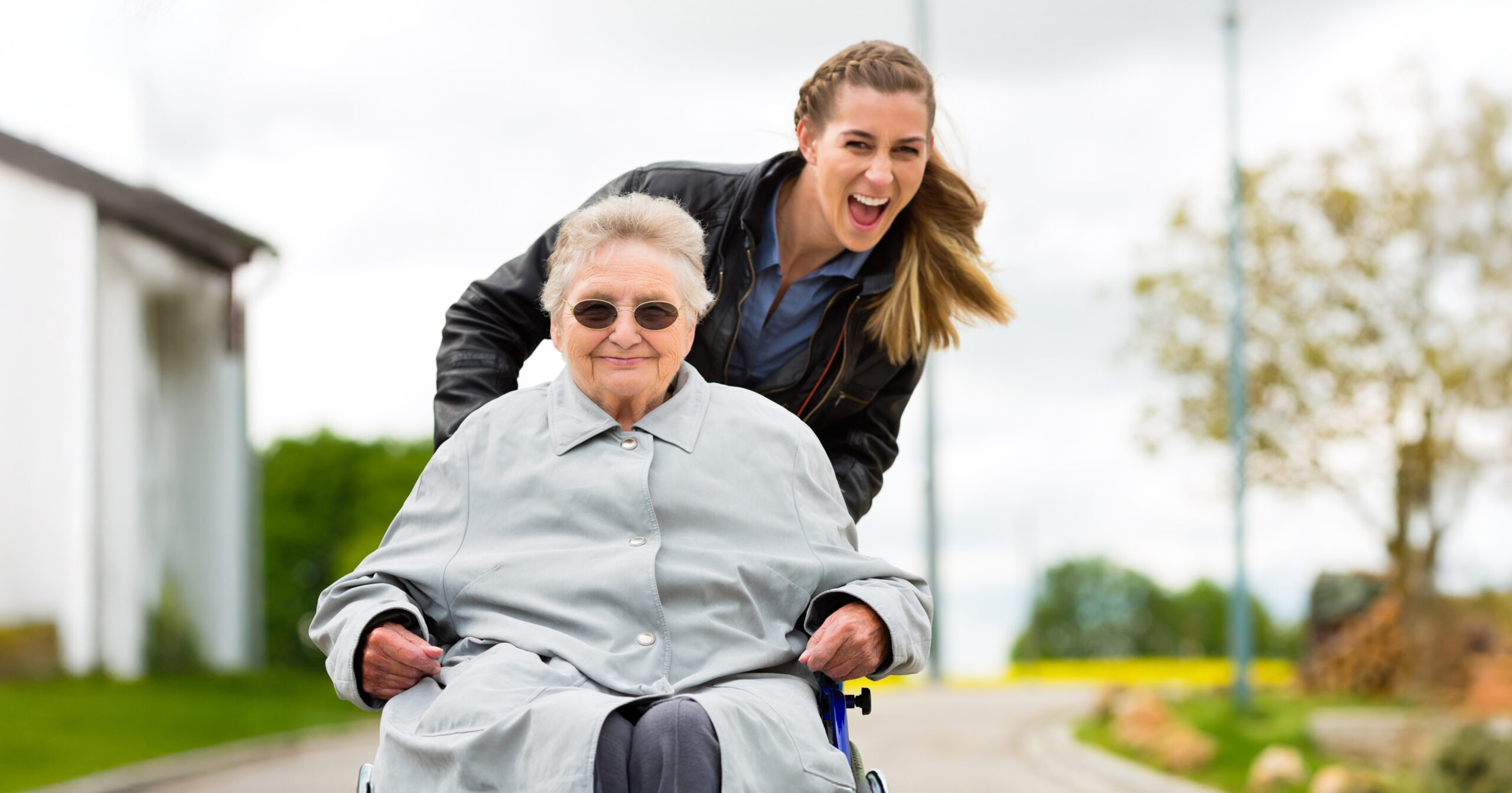 caregiver pushing a senior woman in a wheelchair smiling