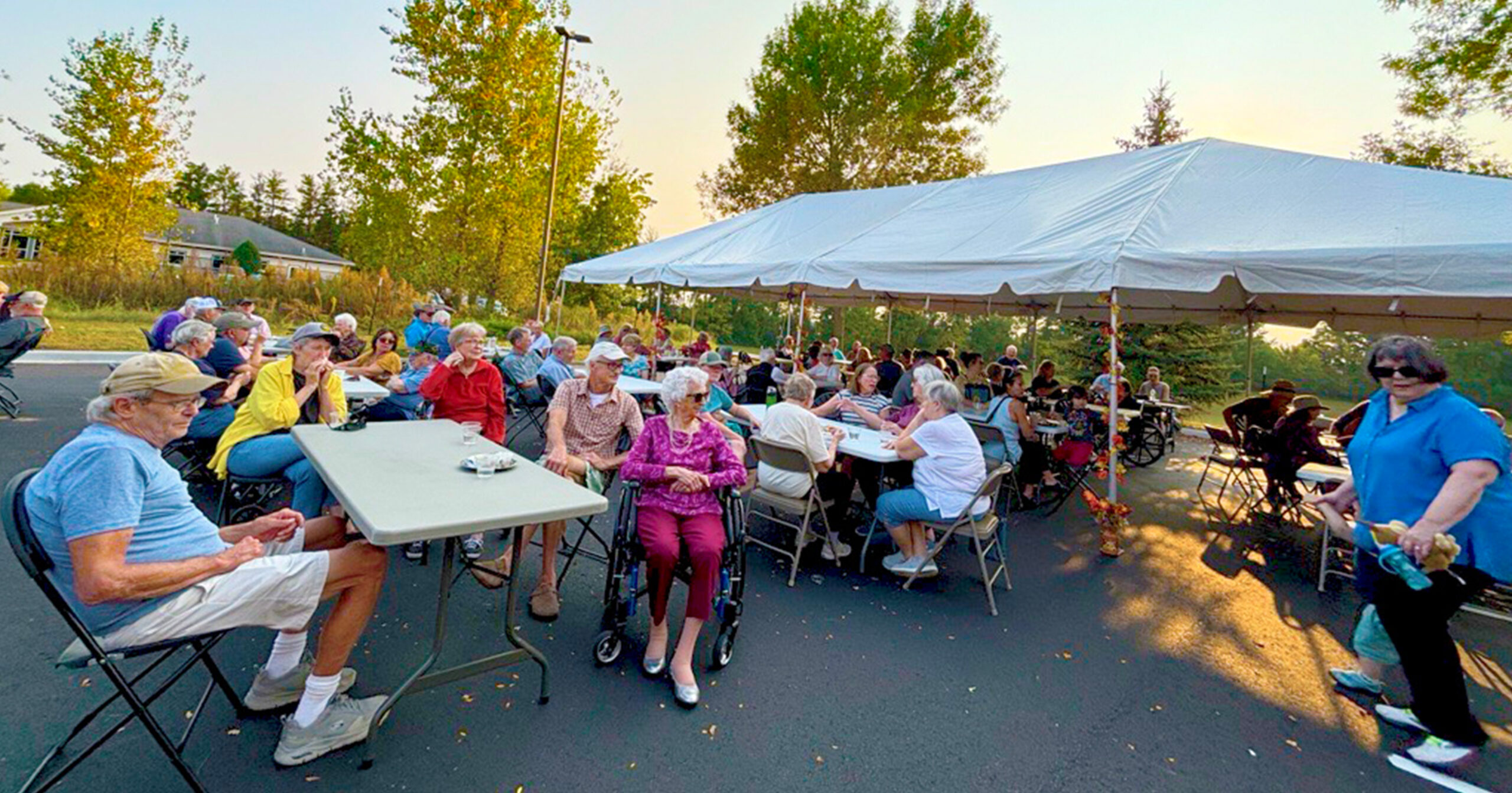 A group of senior adults at an outdoor celebration with food sitting on a patio